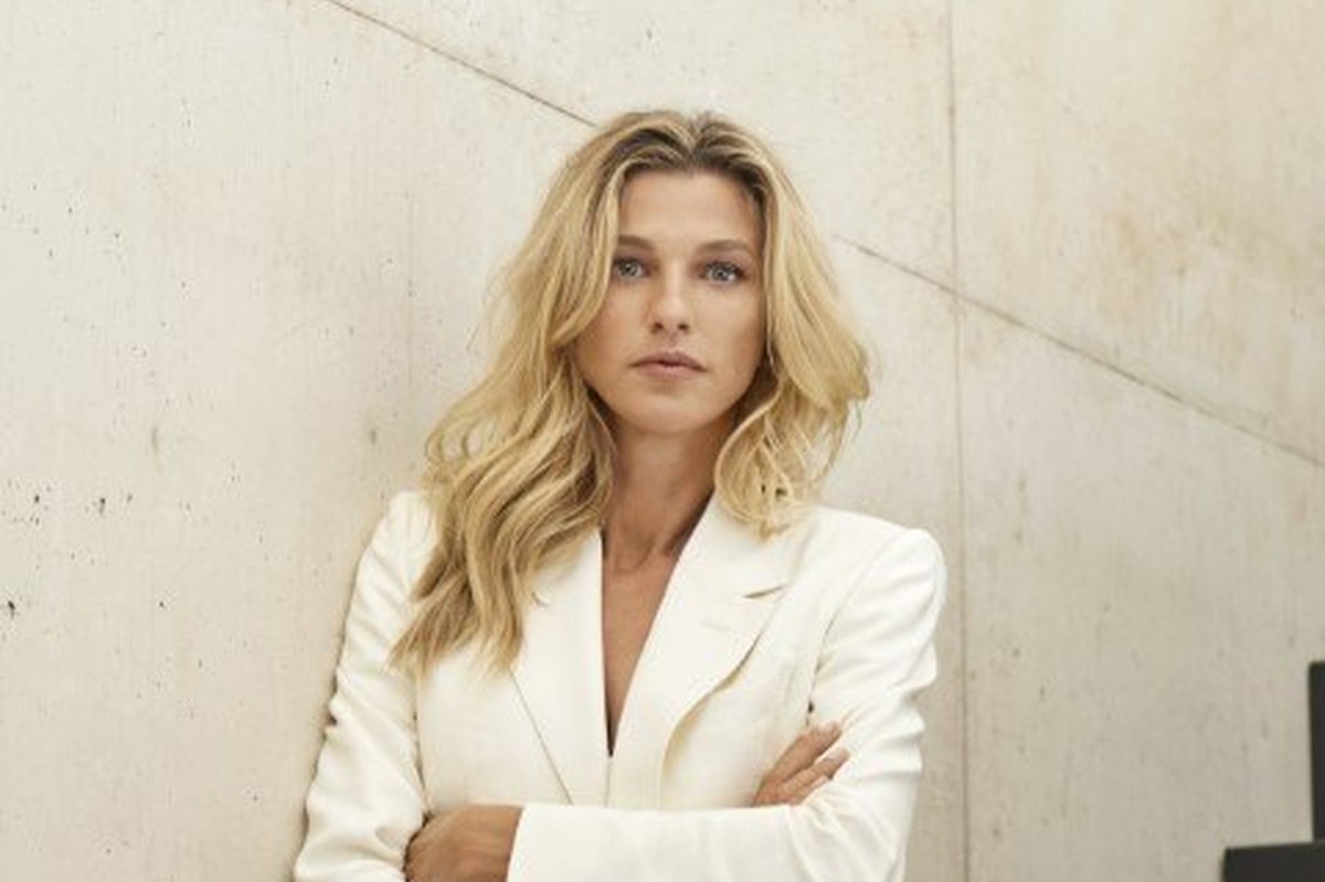 Nicole Junkerman in a cream suit against a pale concrete wall, a calm editorial portrait in daylight